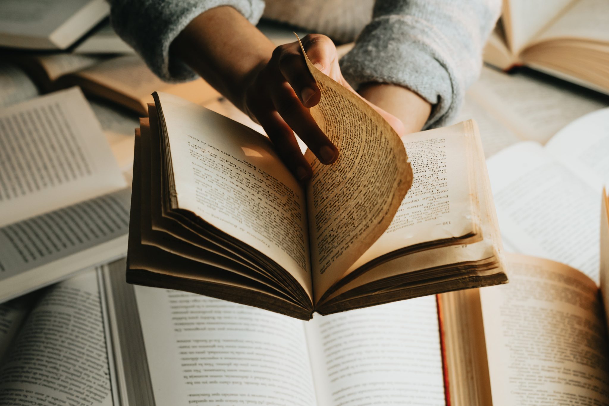 Browse Free HD Images of Person Holds A Book Over A Stack And Turns The Page